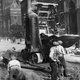 Circa 1925: Workmen repairing a road, with the aid of a cement mixer.